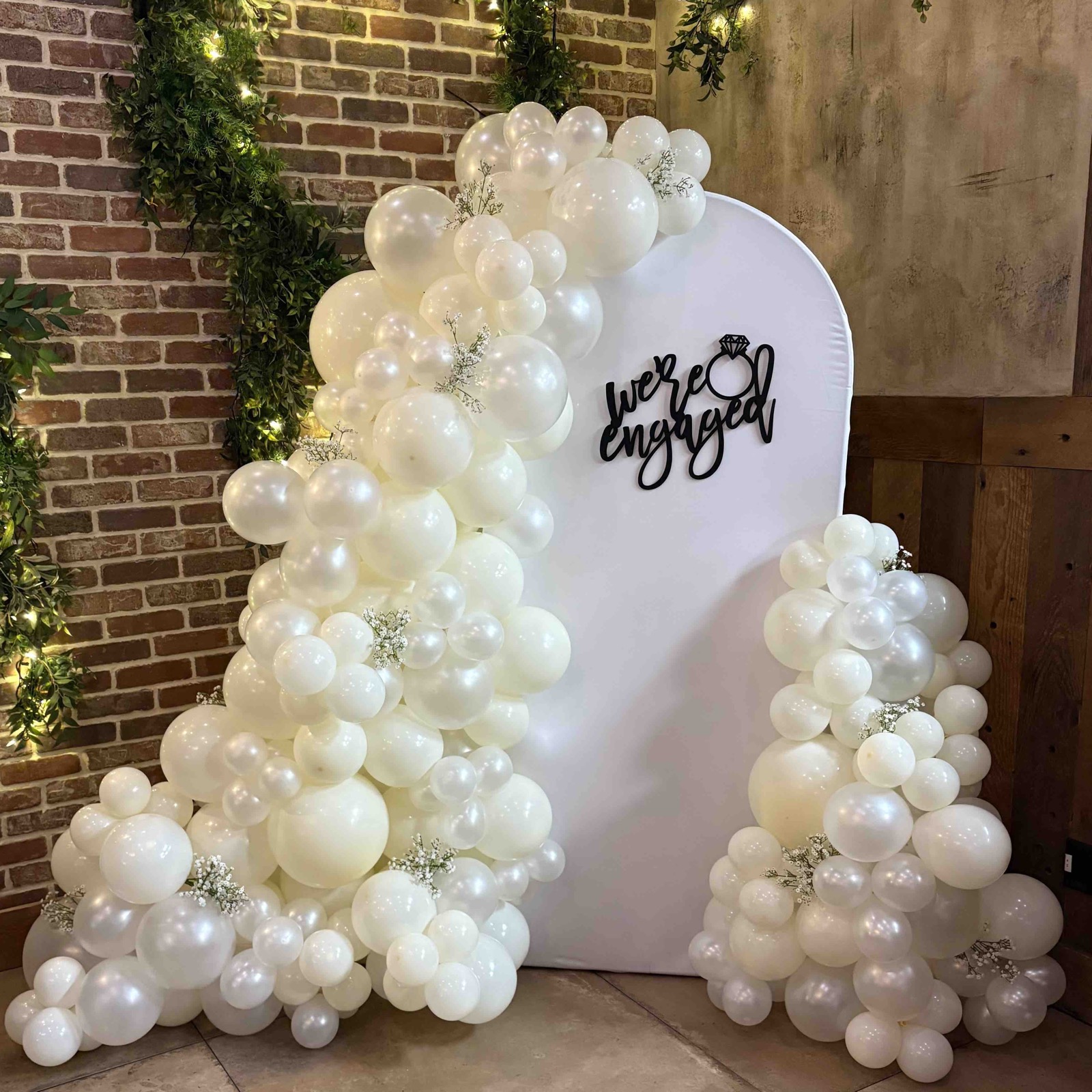 Organic white balloon arch on brick backdrop